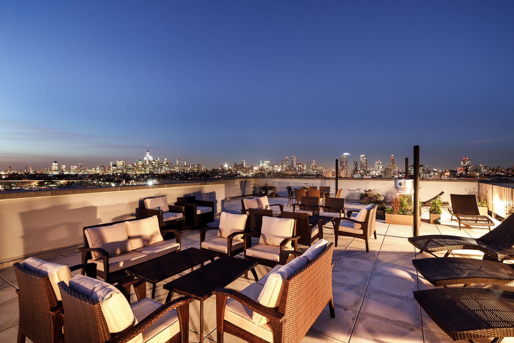Rooftop deck with ample seating and lounge chairs at night with city views